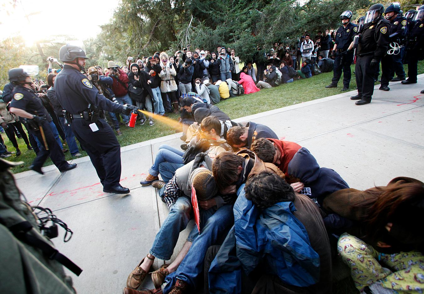 In this Friday, Nov. 18, 2011, photo University of California, Davis Police Lt. John Pike uses pepper spray to move Occupy UC Davis protesters while blocking their exit from the school